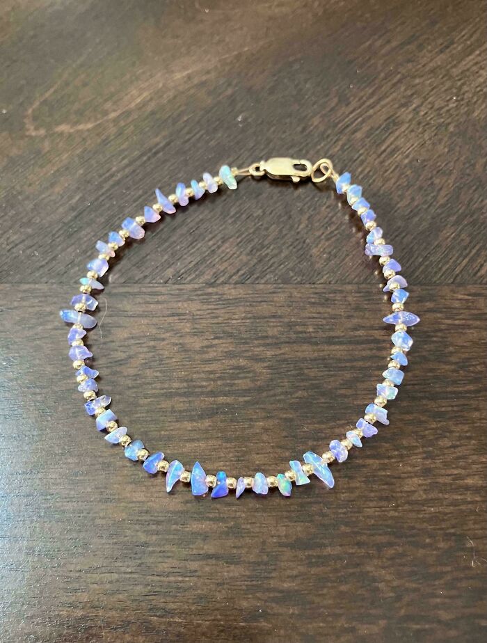 Beaded bracelet with iridescent stones and gold clasp on a wooden surface