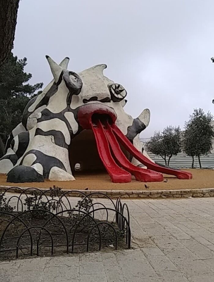 A playground fail featuring a monstrous, black and white structure with two red slides protruding from its mouth.