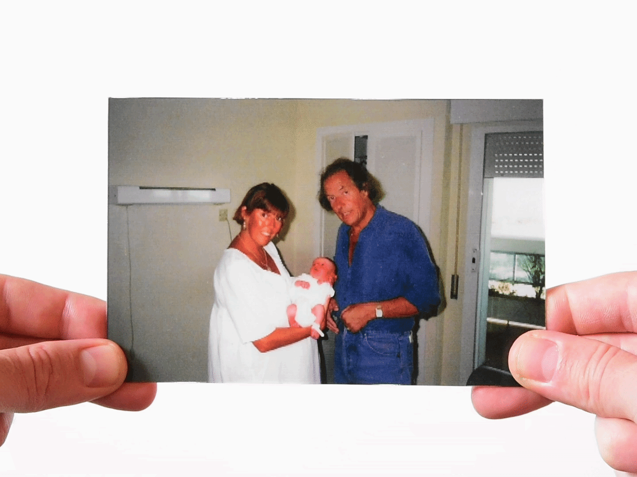 Vintage photo of parents holding a baby indoors for childhood photo memory