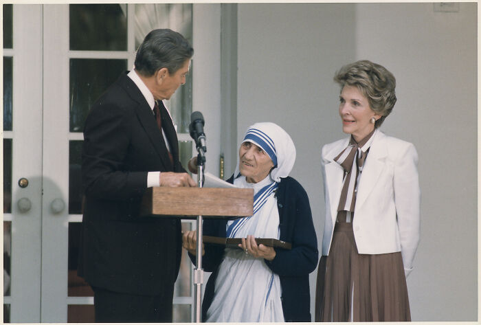 Mother Teresa, a revered figure among Women In History, stands with Ronald Reagan and Nancy Reagan at a podium.