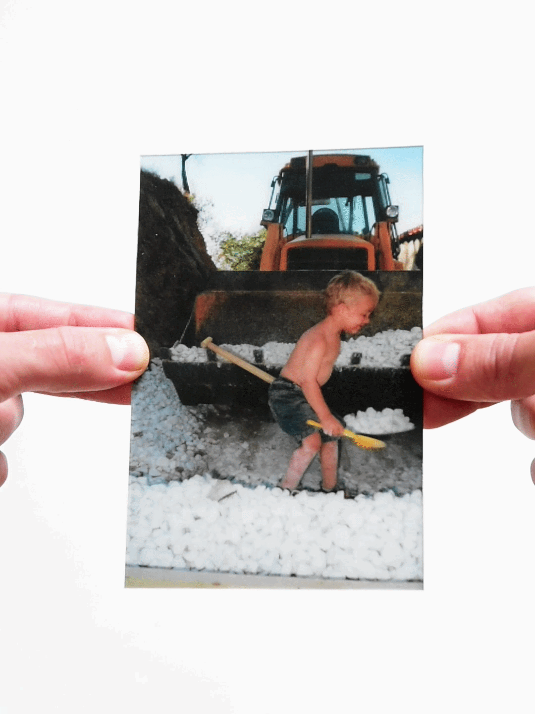 Young child playing with shovel by tractor in edited childhood photo