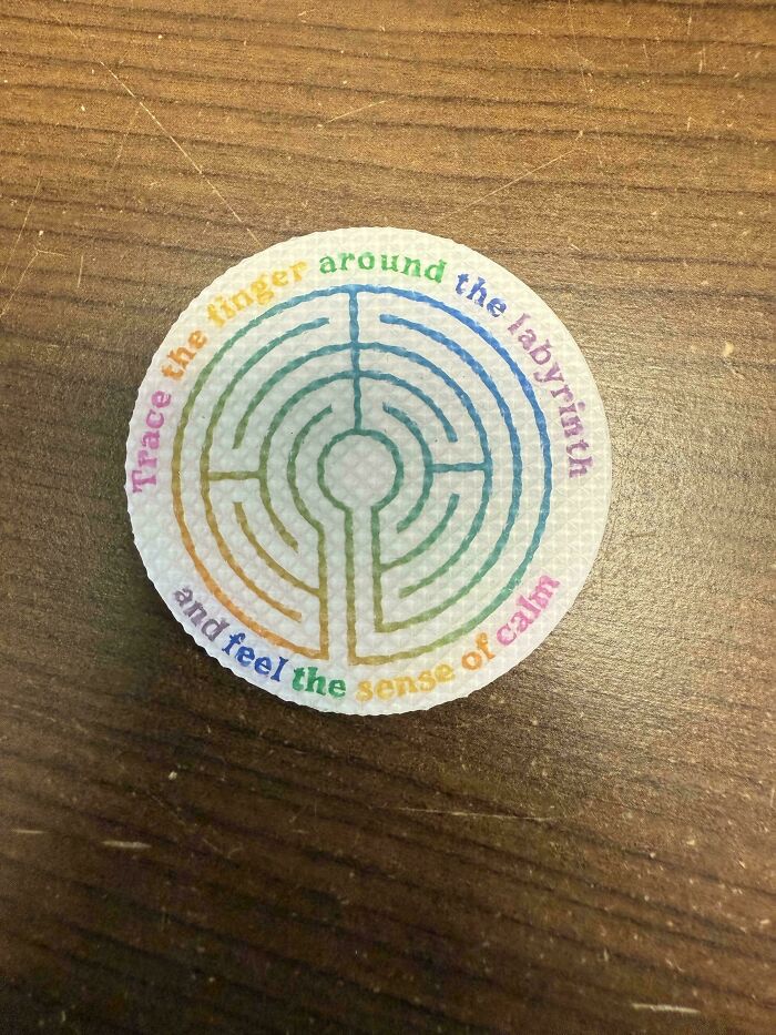 A circular sticker with a rainbow labyrinth design, featuring the text Trace the finger around the labyrinth and feel the sense of calm, highlighting design fails.