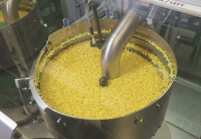 A machine processes a large quantity of small yellow pieces, resembling forbidden food.