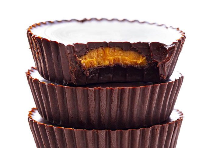 Stack of peanut butter chocolate cups with one partially bitten showing filling