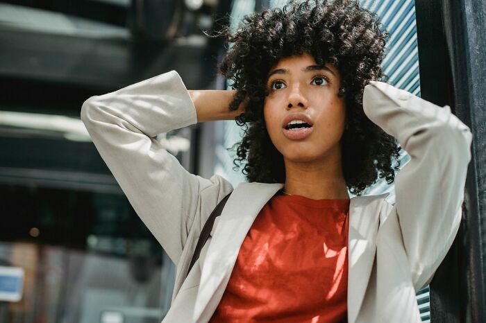 A woman with curly hair looks surprised, possibly reacting to being served delicious dinner or hot tea.