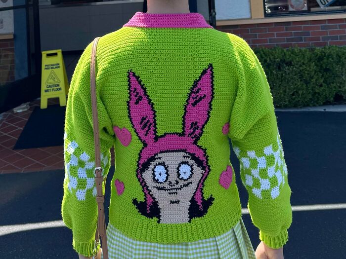 Bright green crocheted sweater with cartoon bunny design on back