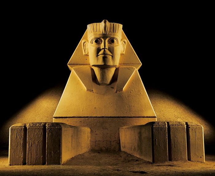 Surreal Japanese playground at night featuring a sphinx-like statue illuminated from below, captured by Fujio Kito.