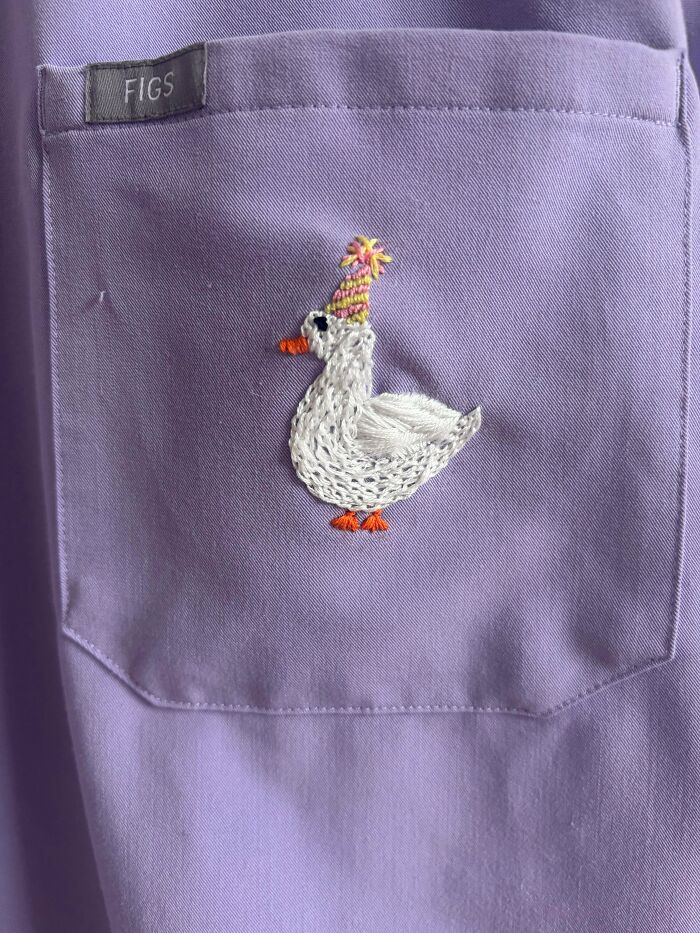 Close-up of embroidered disco goose on purple scrub pocket quirky projects
