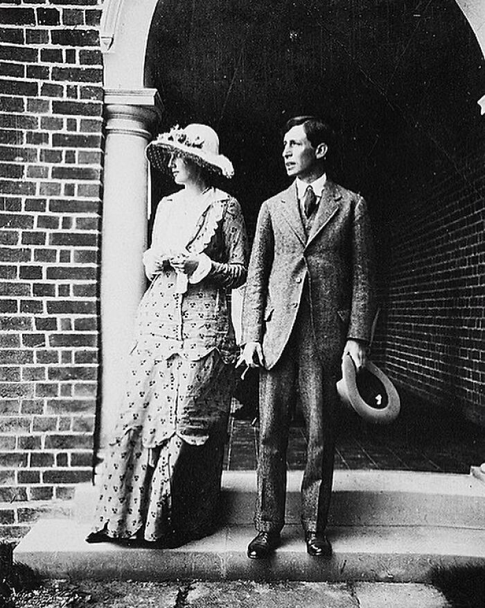 A black and white photo of Eleanor Roosevelt, a prominent figure among Women in History, standing beside her husband, Franklin D. Roosevelt, on a porch.