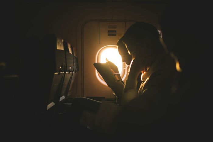 A person looking out an airplane window at sunset, a quiet moment during an airline seating lottery flight.