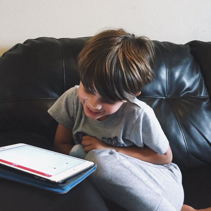 Smiling child looking at a tablet, representing what children were going through and parents opening up.