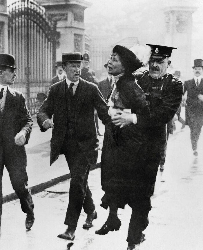Emmeline Pankhurst, a powerful woman in history, being arrested by a policeman during a protest.