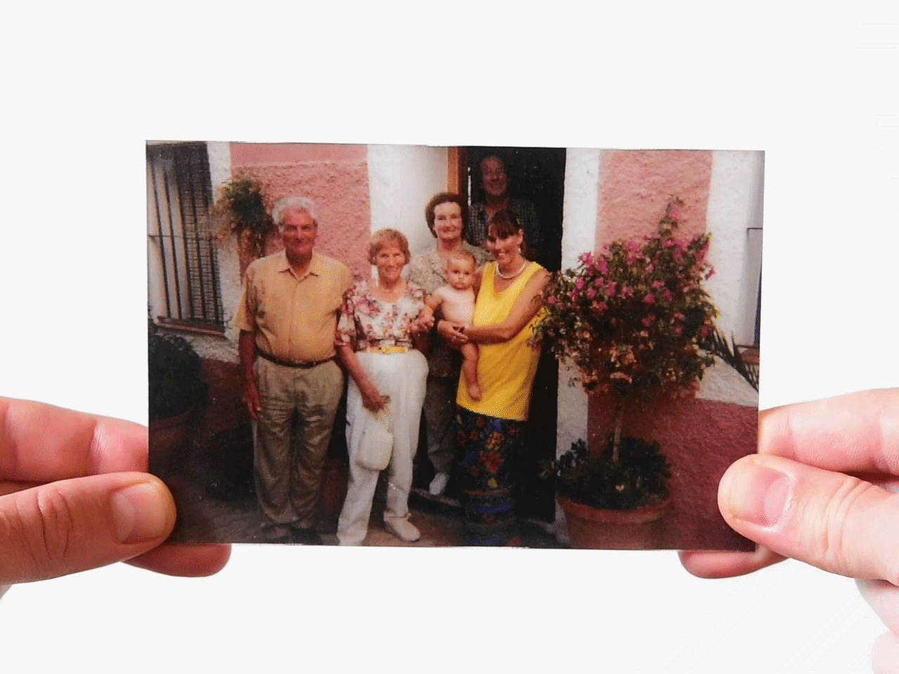 Family group photo in front of house with flowers and pink wall