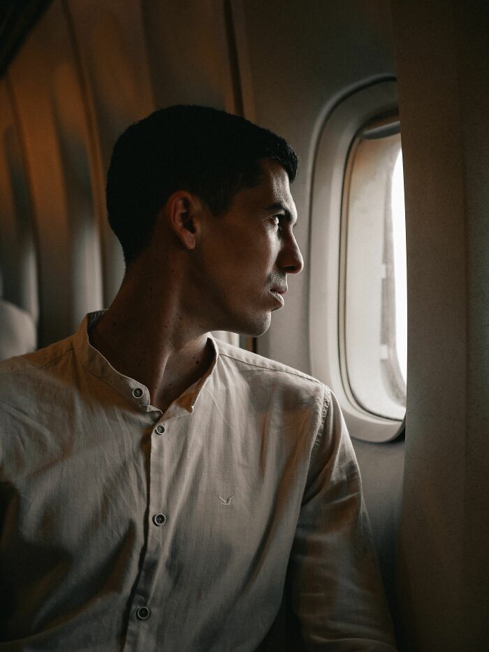 A man looking intently out an airplane window, perhaps contemplating entitled people who got a reality check.