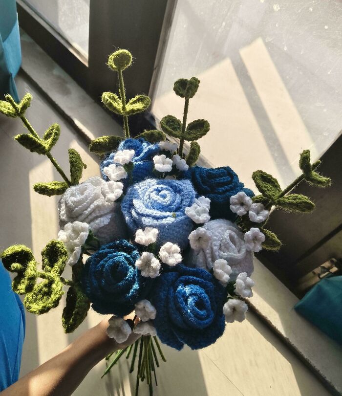 Hand holding bouquet of blue and white crocheted flowers