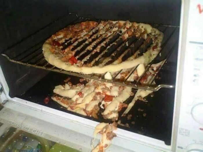 A pizza collapsing through an oven rack into the bottom of the oven, demonstrating a kitchen fail.