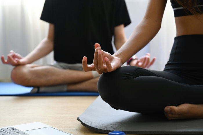 Two people meditating indoors practicing yoga for relaxation