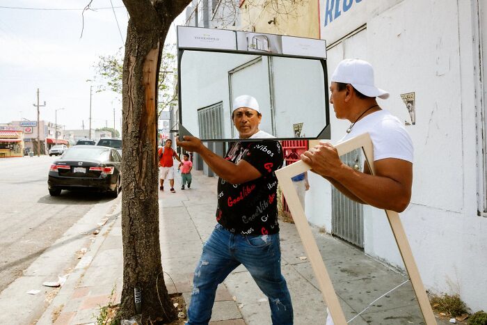 Two men carry large mirrors down a street, creating an interesting visual in these perfectly timed street photos.