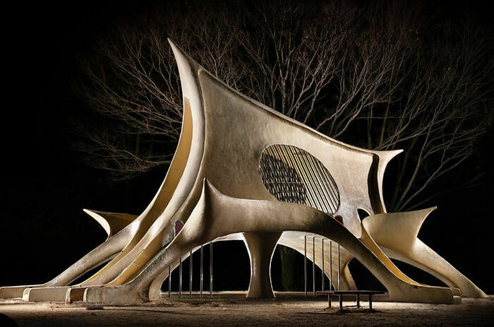 Surreal Japanese playground at night featuring an abstract, sculptural slide by Fujio Kito.