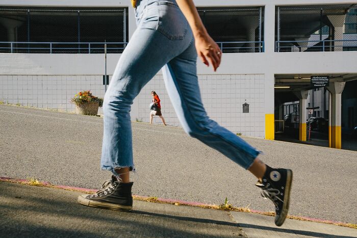 Perfectly timed street photo by Jeremy Paige of a person walking up a hill with another person in the background.