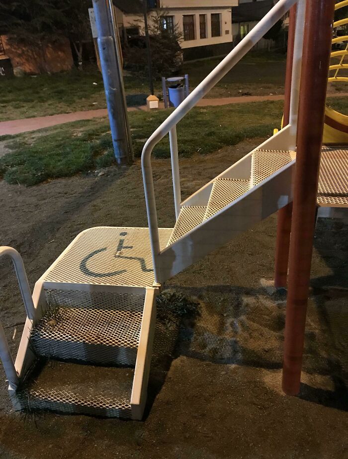 A short set of stairs on a playground platform with a wheelchair access symbol, a clear playground fail.