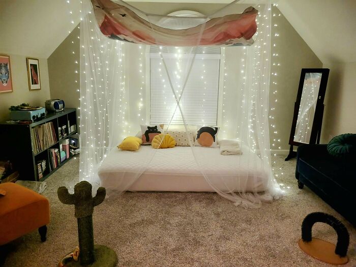 Cozy bedroom with bed draped in fairy lights and sheer canopy