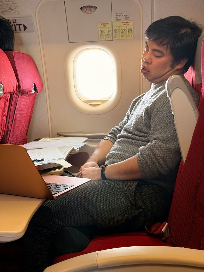 A man sleeping on an airplane with a laptop on his tray table, depicting entitled people who got a reality check.
