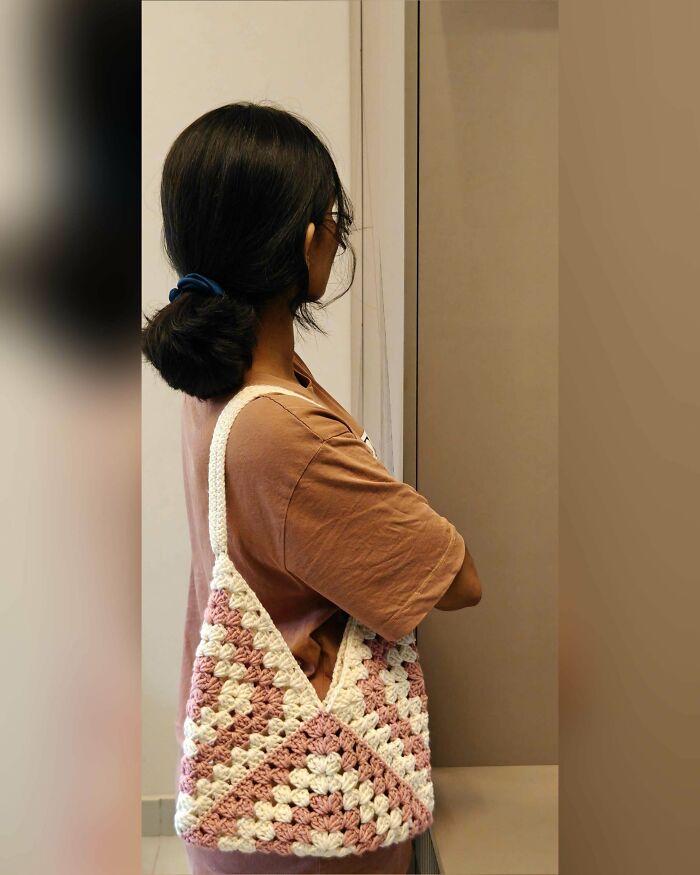 Woman carrying a handmade crocheted triangular bag over shoulder