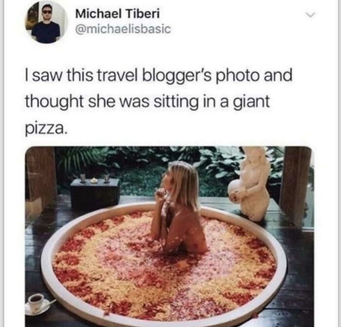 A woman soaking in a tub filled with what looks like forbidden foods, resembling a giant pizza.