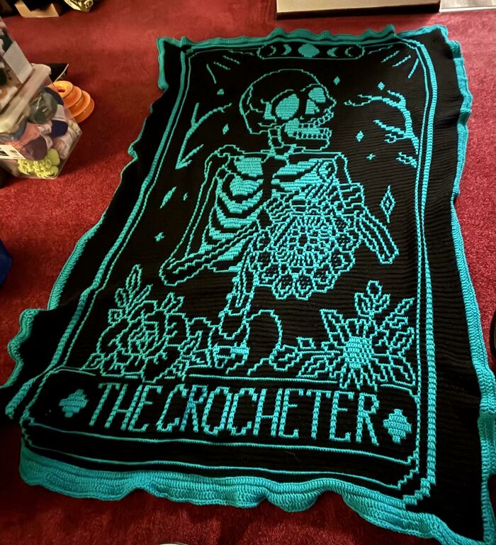 Black and teal crochet blanket featuring a skeleton design and words the crocheter