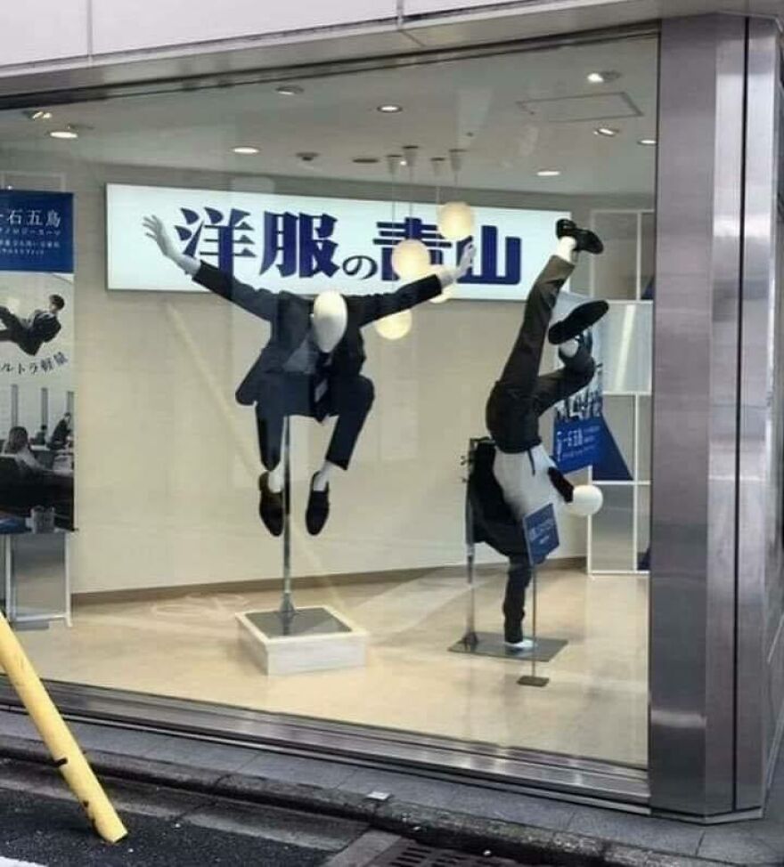 Two mannequins in suits displayed in a store window, appearing to float and perform acrobatic moves, creating a chaotic pic.
