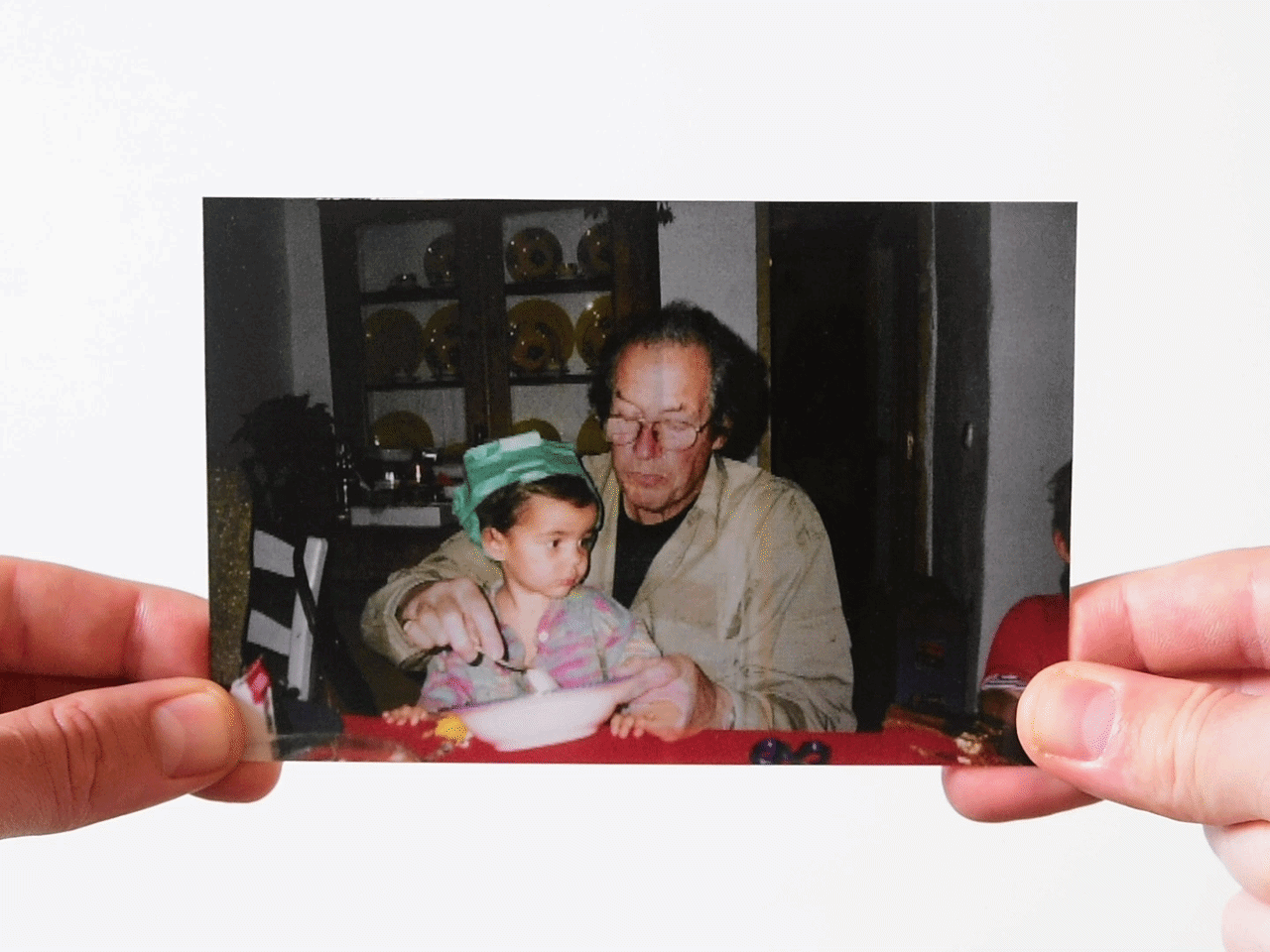 Father feeding a young child sitting at a table with a bowl
