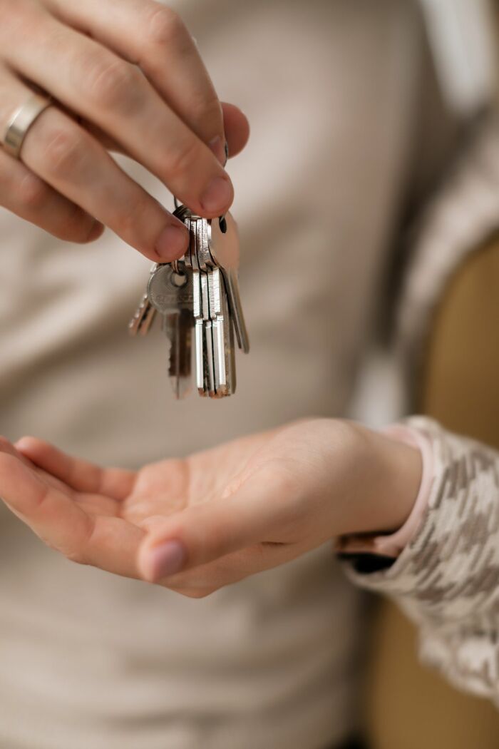 A hand holding a set of keys, offering them to another person. Safety tips for women living alone.