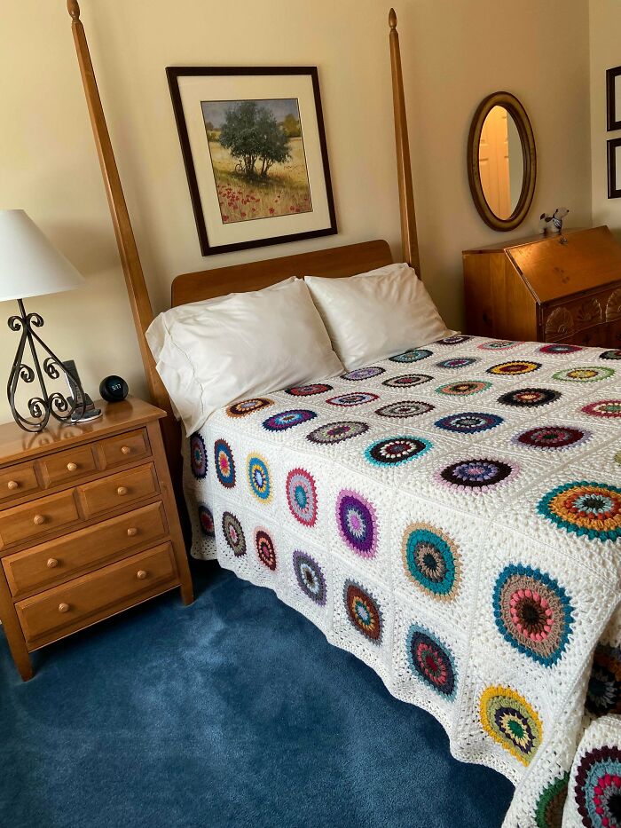 Crocheted multicolored circle pattern blanket on a wooden bed