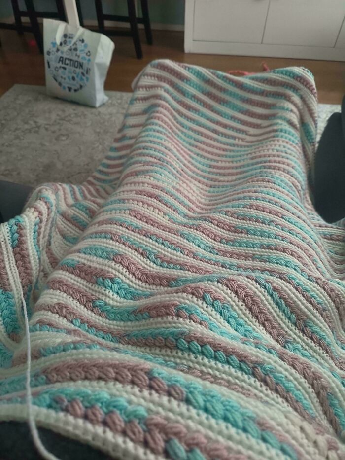 Soft pastel striped crochet blanket draped over sofa cushions