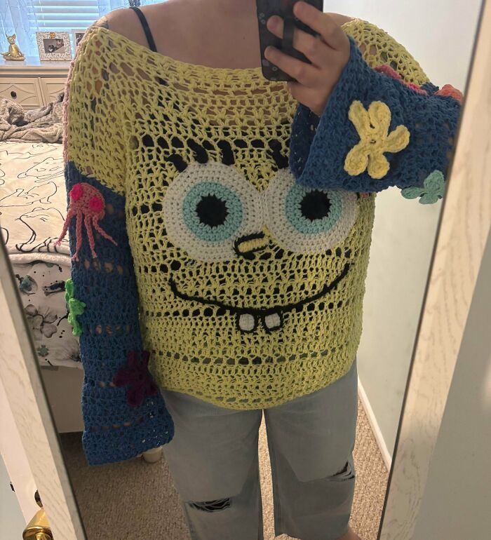 Crocheted sweater featuring a SpongeBob face with floral sleeves and colorful details