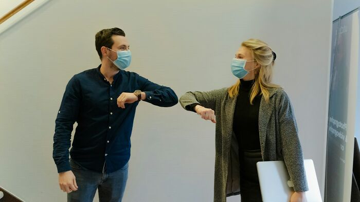 Two people bumping elbows, symbolizing new social norms that affect airline seating lottery experiences.