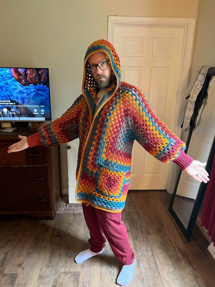 Colorful crocheted hooded jacket worn by person indoors