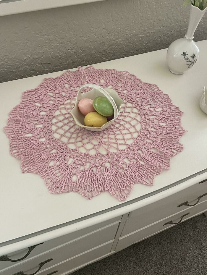 Pink crocheted doily centerpiece with pastel eggs in a small bowl