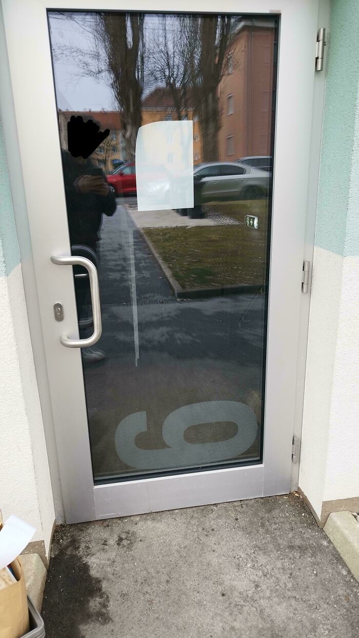A glass door with a large backward number nine as a design fail for a street number.