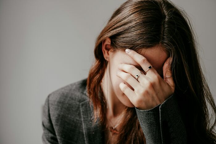 Woman covering face with hand showing emotional distress or frustration
