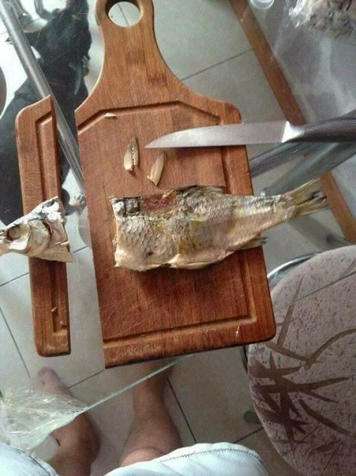 A partially filleted fish on a wooden cutting board, part of a kitchen fail in meal prep.