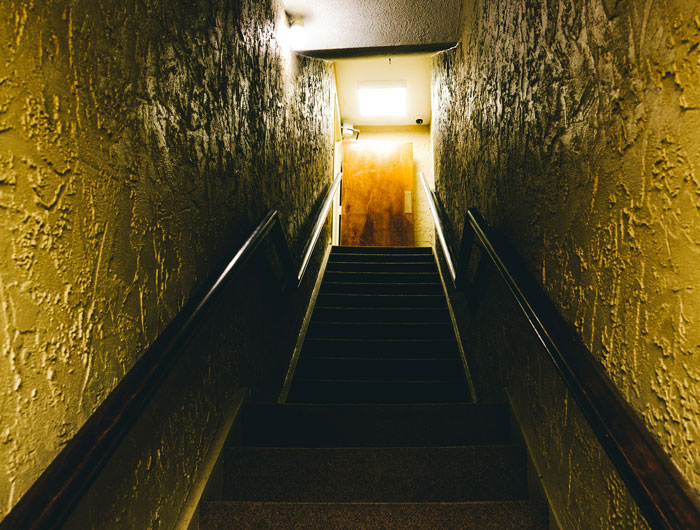 A dark, foreboding staircase with textured walls, hinting at nightmarish tenant stories landlords experience.