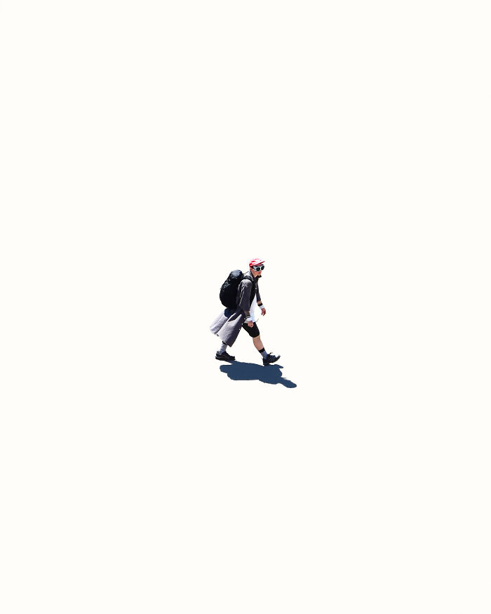 A photographer uses negative space to capture a person walking with a backpack on a minimalist white background.
