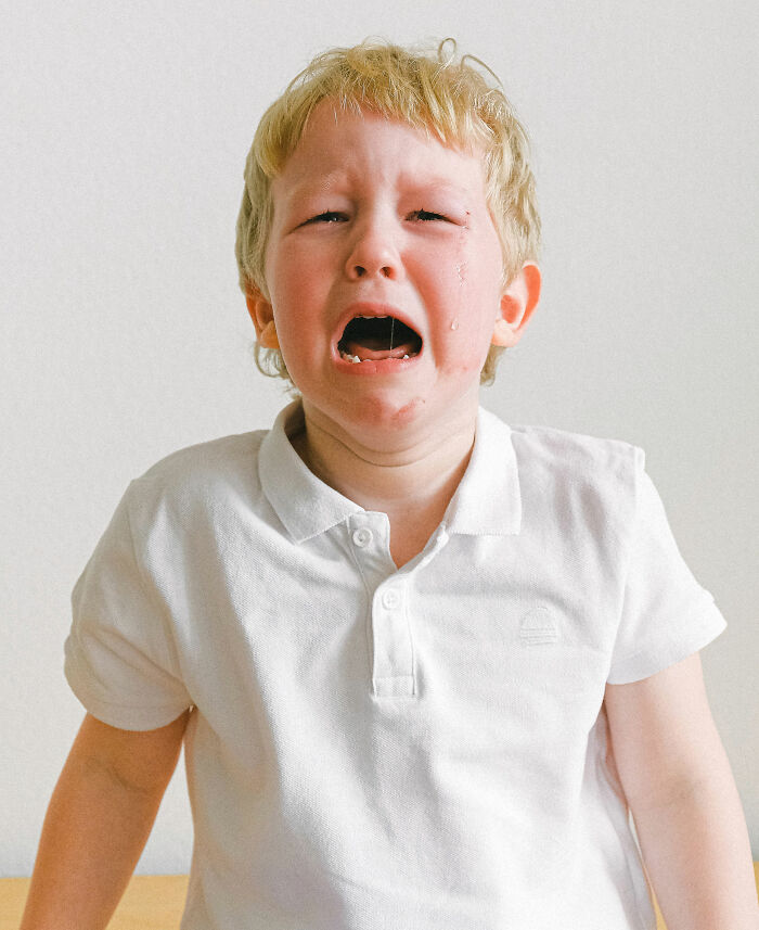 A young blonde boy crying loudly, representing entitled people getting a reality check.