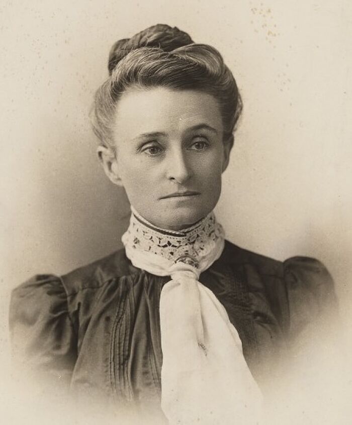 Sepia-toned portrait of a woman with an elegant updo and a lace cravat, highlighting women in history.