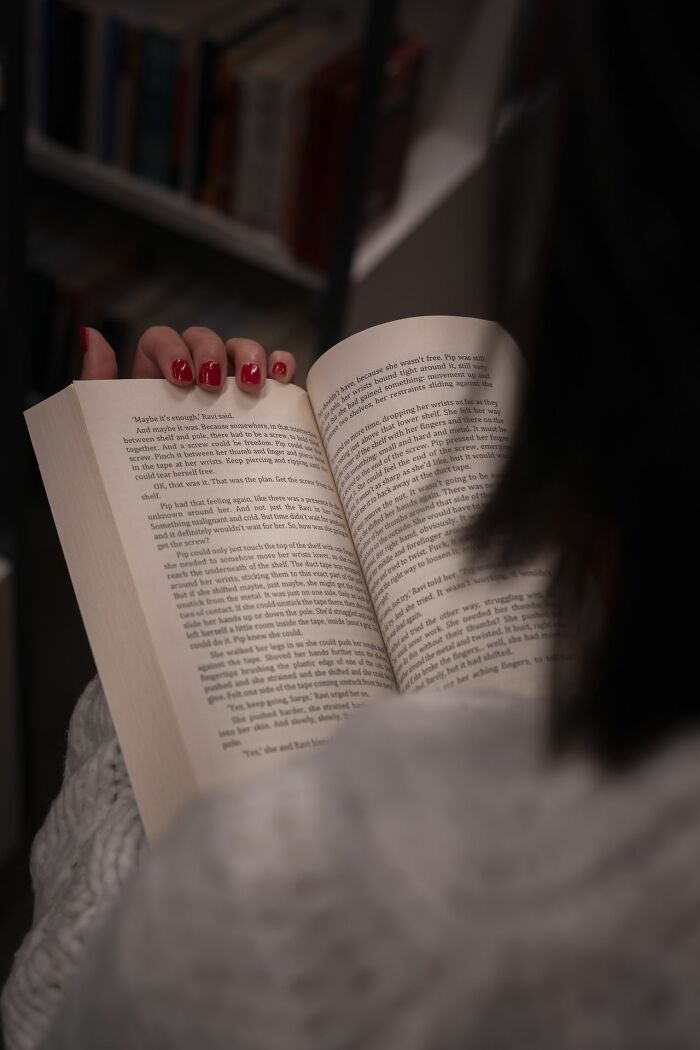 A woman living alone reading a book, as women living alone can use safety tips to protect themselves.