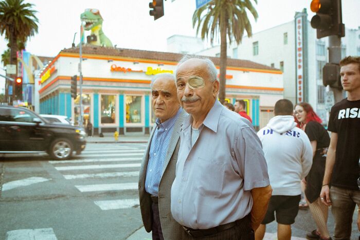 Perfectly timed street photo by Jeremy Paige of two older men on a city street, one with an eyepatch.