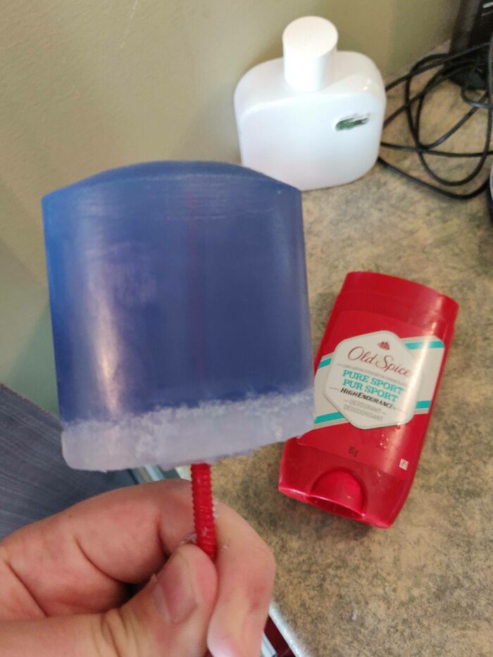 A hand holds a blue deodorant stick, shaped like a popsicle, next to a red Old Spice deodorant stick. Forbidden foods.
