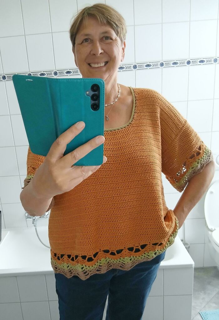 Orange crochet top with decorative edging worn by smiling woman